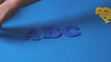Childs hand playing with letters of the alphabet. Blue-yellow letters of the alphabet. School start.