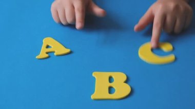 The child plays with the letters of the alphabet. yellow letters ABC on a blue background. High quality FullHD footage