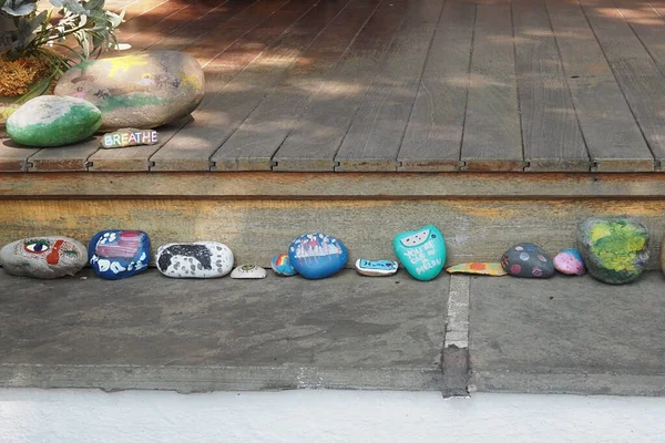 The painted stones are on the step in front of the porch.