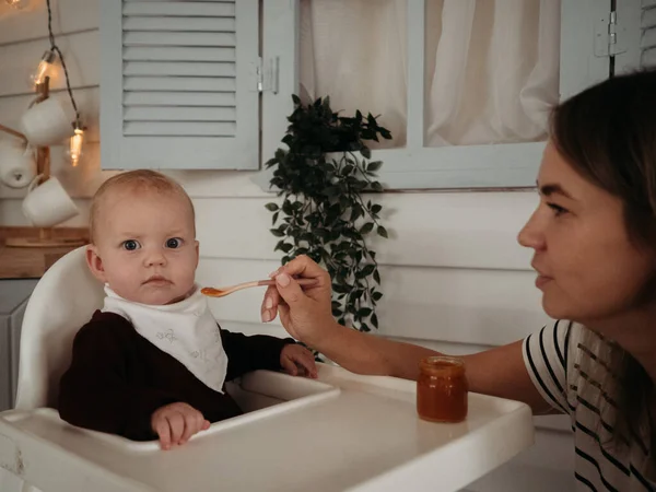 Anne ve bebek. Anne bebeği besliyor, ilk besleme, ilk kaşık