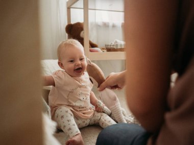 Anne ve bebek, bebek yumuşak oyuncaklarla oynar ve güler.