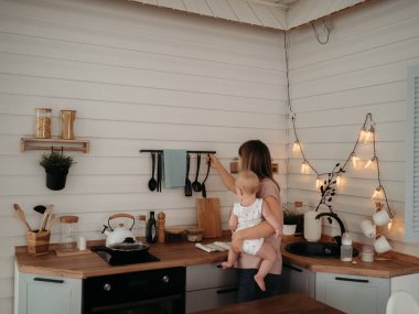 Anne ve bebek. Kollarında çocuğu olan bir anne yemek hazırlıyor, çocuk maması.