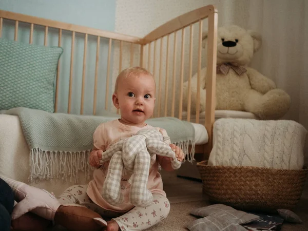 Anne ve bebek, bebek yumuşak oyuncaklarla oynar ve güler.