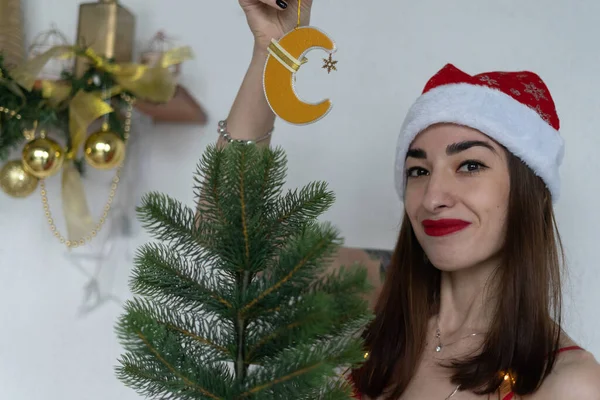 Genç bir kadın yeni yılda Noel ağacını süslüyor.