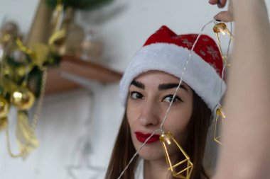 Genç bir kadın yeni yılda Noel ağacını süslüyor.