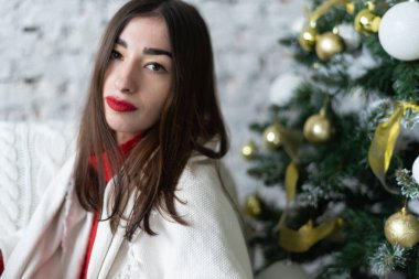 Genç bir kadın yeni yılda Noel ağacını süslüyor.