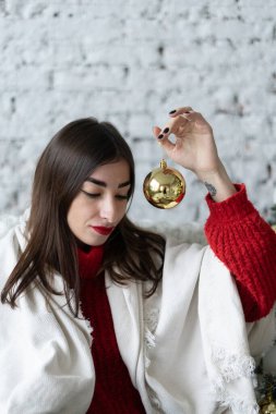 Genç bir kadın yeni yılda Noel ağacını süslüyor.