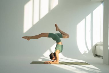 Kız yoga yapıyor, jimnastik yapıyor ve esneme hareketleri yapıyor.