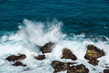 rough ocean waves crashing on rocks at coast or beach