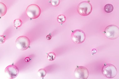 Pembe toplar pembe masa arkasında yüzer. Noel kompozisyonu. Düzlük, üst manzara, yeni yıl ve noel indirimi kartı..