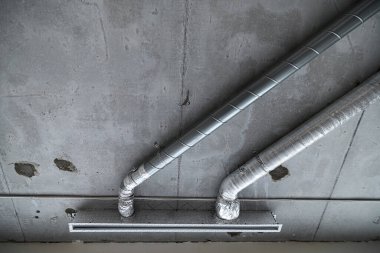 İnşaat halindeki bir evin beton tavanındaki havalandırma borularının kabloları. Odanın inşaatı devam ediyor. Duvarları alçılı, zemini betondan ve tavanı da betondan..