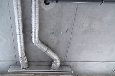 İnşaat halindeki bir evin beton tavanındaki havalandırma borularının kabloları. Odanın inşaatı devam ediyor. Duvarları alçılı, zemini betondan ve tavanı da betondan..