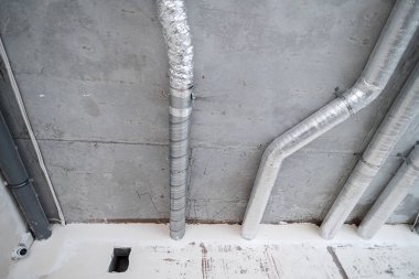 İnşaat halindeki bir evin beton tavanındaki havalandırma borularının kabloları. Odanın inşaatı devam ediyor. Duvarları alçılı, zemini betondan ve tavanı da betondan..
