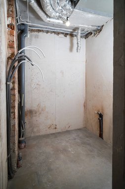 İnşaat halindeki bir evin beton tavanındaki havalandırma borularının kabloları. Odanın inşaatı devam ediyor. Duvarları alçılı, zemini betondan ve tavanı da betondan..