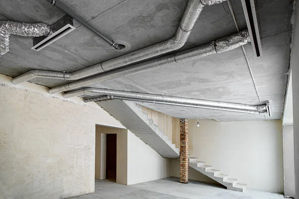 部屋は 大まかな仕上げ 漆喰の壁 コンクリートの床で建設中です 建設中の家のコンクリート天井に換気管の配線 — ストック写真