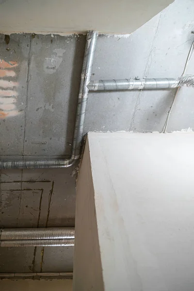 工事中の家のコンクリート天井に換気管の配線 部屋は大まかな仕上げ 漆喰壁 コンクリートの床と天井で建設中です — ストック写真