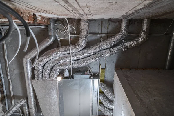 İnşaat halindeki bir evin beton tavanındaki havalandırma borularının kabloları. Odanın inşaatı devam ediyor. Duvarları alçılı, zemini betondan ve tavanı da betondan..