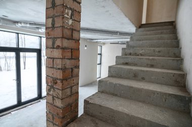 Yeni inşa edilmiş bir binanın ikinci katına çıkan merdivenler. Odanın inşaatı sürüyor. Duvarları alçılı, zemini beton..