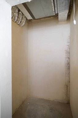 Yeni inşa edilmiş bir binada teknik ihtiyaçlar için küçük bir oda. Boru tesisatı. Odanın inşaatı sürüyor. Duvarları alçılı, zemini beton..