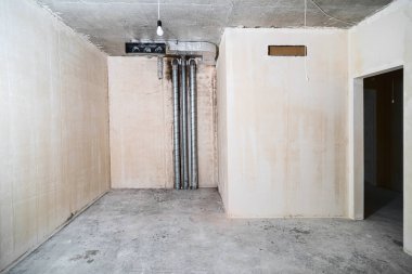 Yeni inşa edilmiş bir binada inşaat halindeki boş bir oda. Kışın inşaat halindeki bir ev. Odanın inşaatı sürüyor. Duvarları alçılı, zemini beton..