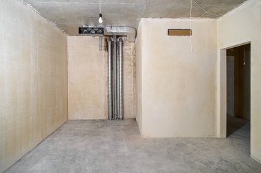 Yeni inşa edilmiş bir binada inşaat halindeki boş bir oda. Kışın inşaat halindeki bir ev. Odanın inşaatı sürüyor. Duvarları alçılı, zemini beton..