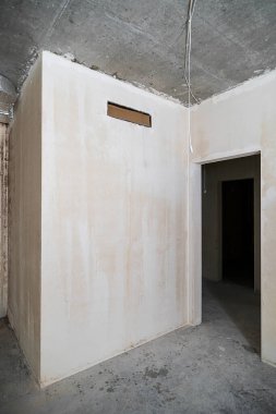 Yeni inşa edilmiş bir binada inşaat halindeki boş bir oda. Kışın inşaat halindeki bir ev. Odanın inşaatı sürüyor. Duvarları alçılı, zemini beton..