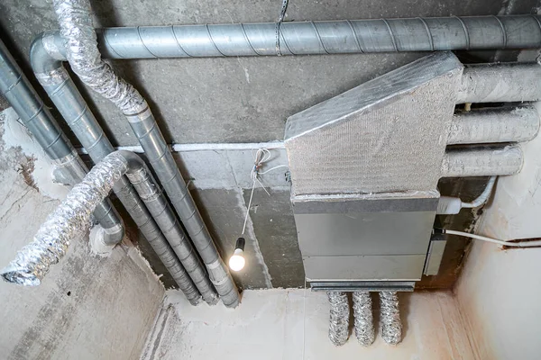 İnşaat halindeki bir evin beton tavanındaki havalandırma borularının kabloları. Odanın inşaatı devam ediyor. Duvarları alçılı, zemini betondan ve tavanı da betondan..