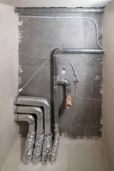 İnşaat halindeki bir evin beton tavanındaki havalandırma borularının kabloları. Odanın inşaatı devam ediyor. Duvarları alçılı, zemini betondan ve tavanı da betondan..