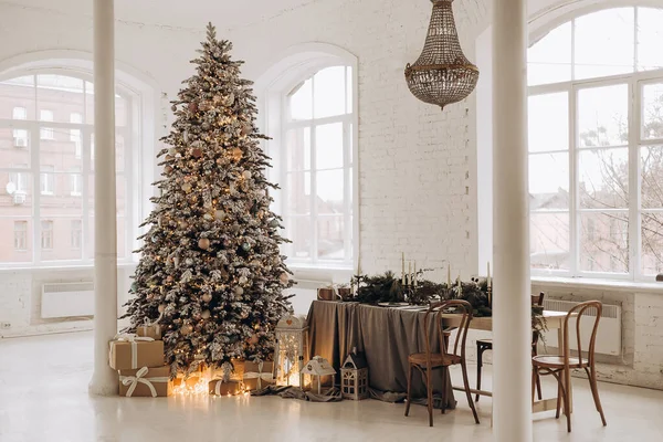 Az újévi ajándékok a fa alatt vannak. Hóval borított fa a kandalló mellett. Szilveszter dekoráció a belső tér. — Stock Fotó