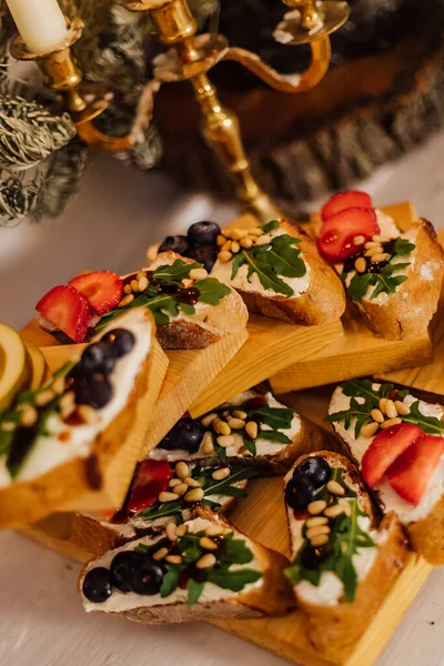 Χριστουγεννιάτικο δείπνο με κεριά. Ιταλική μπρουσκέτα με κρέμα τυριού, φράουλα, ρόκα και σάλτσα βαλσαμικού ξιδιού με μέλι — Φωτογραφία Αρχείου