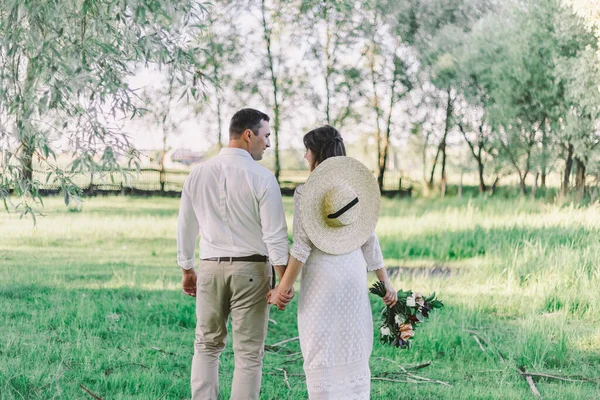 Gelin ve damat parkta yürüyorlar. Düğün, gelin ve damat el ele yürüyorlar.