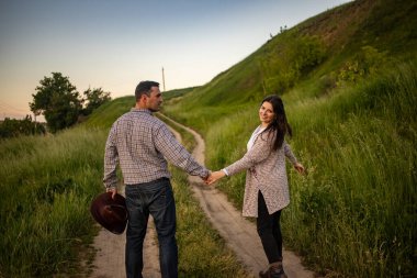 Yakışıklı bir adam ve çekici genç bir kadın güneşli bir günde karlı köy yolunda yürüyor. Güzel görünüş, erkek ve kadın modası, kış kıyafeti. Kış tatili, kırsal alanda hafta sonu konsepti.