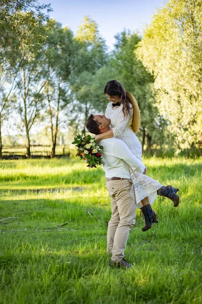 Tarz sahibi mutlu gelin, damat kucağına alınmış ve dans ediyor. Damat gelini kaldırdı ve döndürdü.