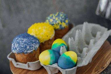 Ukrayna bayrağının renginde paskalya pastaları, yumurta ve paskalya yumurtaları olan karton bir stantta sarı ve mavi. mesaj için yer. seçici odak.