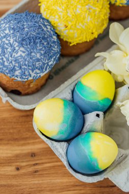 Ukrayna bayrağının renginde paskalya pastaları, yumurta ve paskalya yumurtaları olan karton bir stantta sarı ve mavi. mesaj için yer. seçici odak.