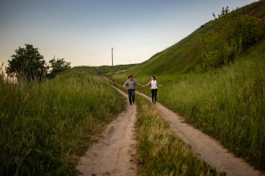 Köy yolunda koşan kırsal giysili bir adam ve bir kız..