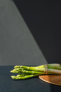 Tahta üzerinde taze yeşil kuşkonmaz dalları, koyu gri arka plan, üst manzara. Kopyalama alanı ile temel eğilim kavramı