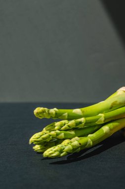 Tahta üzerinde taze yeşil kuşkonmaz dalları, koyu gri arka plan, üst manzara. Kopyalama alanı ile temel eğilim kavramı