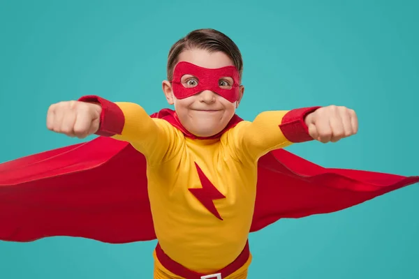 Grappig kind in superheld kostuum met vuisten omhoog — Stockfoto