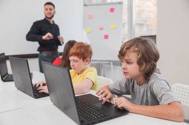 İlkokul öğrencileri sınıfta dizüstü bilgisayarlarla çalışıyorlar.