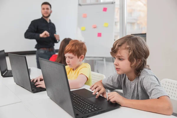 Niños de primaria que trabajan en computadoras portátiles en el aula — Foto de Stock