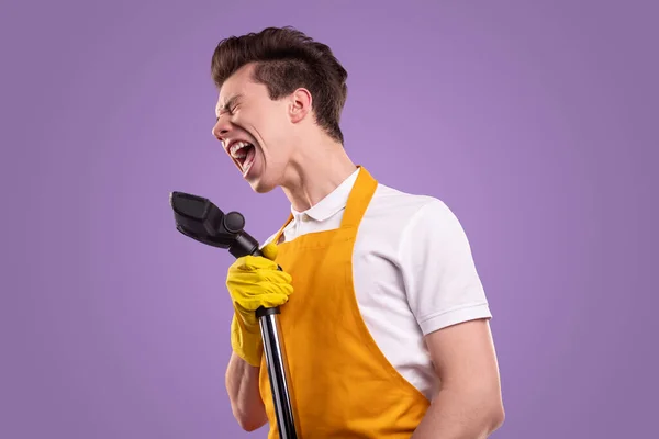 Funny man with vacuum cleaner singing in studio — Stock Photo, Image