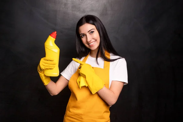 Felice giovane casalinga che indica detergente — Foto Stock
