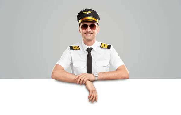 Veselý letec v uniformě opírající se o prázdný štítek — Stock fotografie