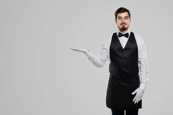 Friendly waiter in gloves on gray background — Stock Photo, Image