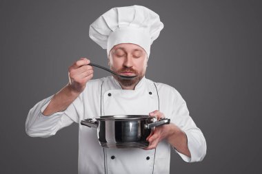 Üniformalı şef yemek tadıyor.