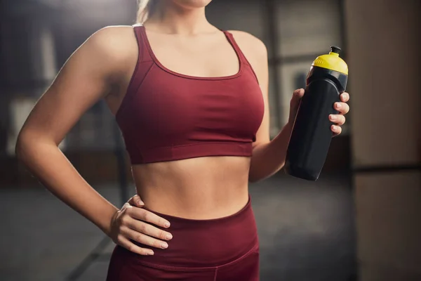 Crop sportswoman with bottle of water in gymnasium — Stock Photo, Image