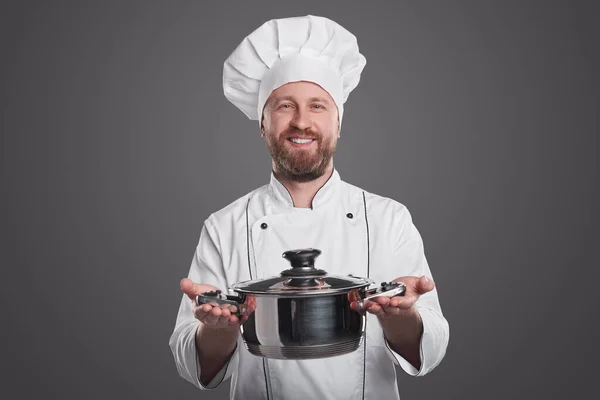 Veselý kuchař s talířkem na šedém pozadí — Stock fotografie