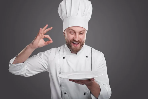 Satisfied chef with plate showing OK gesture — Stock Photo, Image