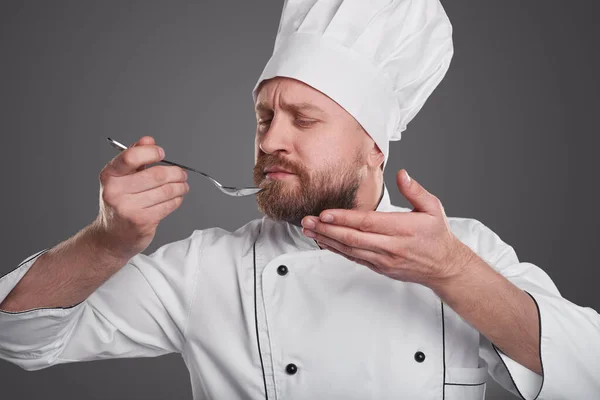 Chef com colher de degustação de alimentos — Fotografia de Stock